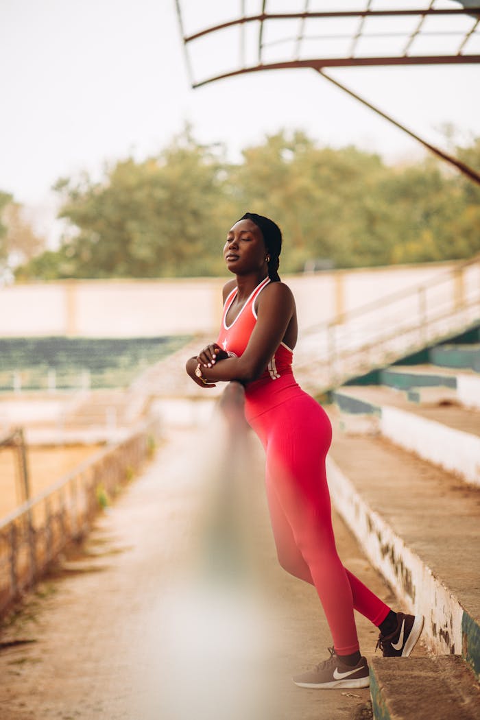 A woman in red athletic wear enjoys a peaceful moment outdoors.